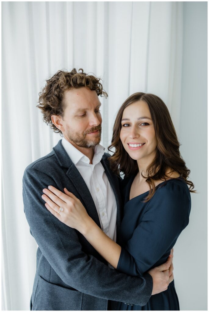 Dana and Zach embracing together inside a bright studio for their winter engagement session in South Bend.