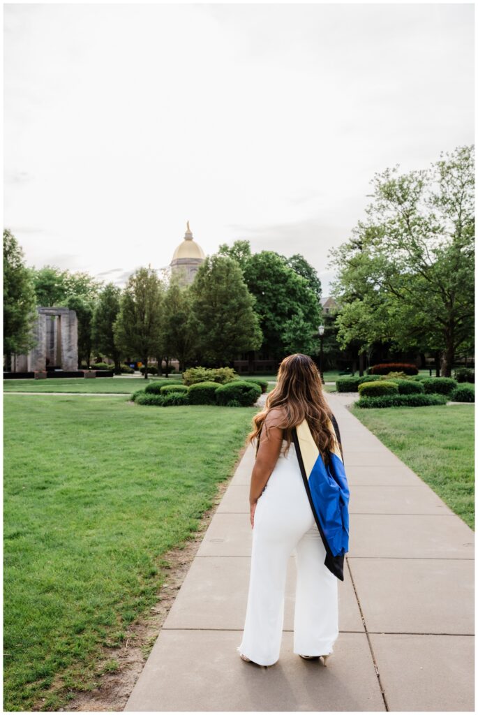 Njeri standing on the University of Notre Dame campus in soft evening light after earning her master’s degree.