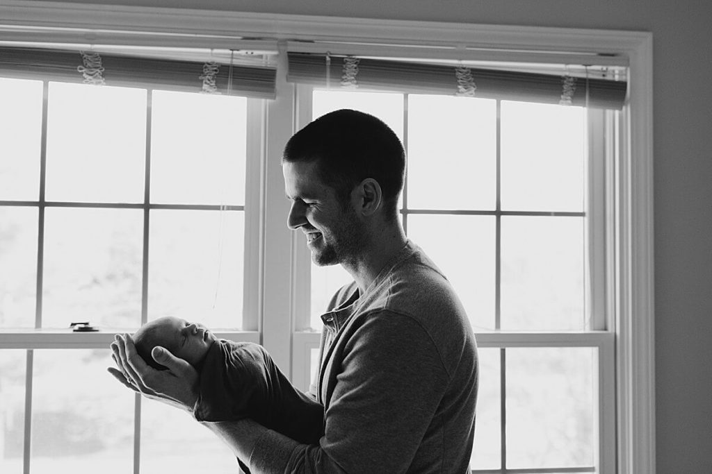 Dad holds newborn in black and white photo during in-home newborn photography session in Carmel indiana